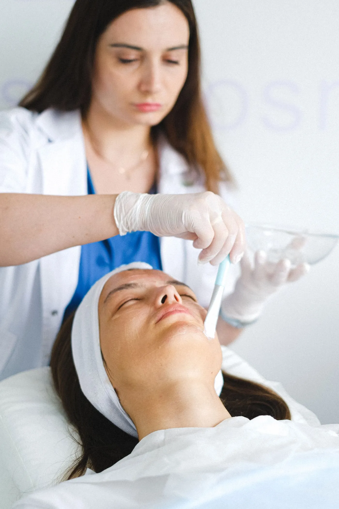 A clinician brushing a chemical peel solution onto a client’s face during treatment