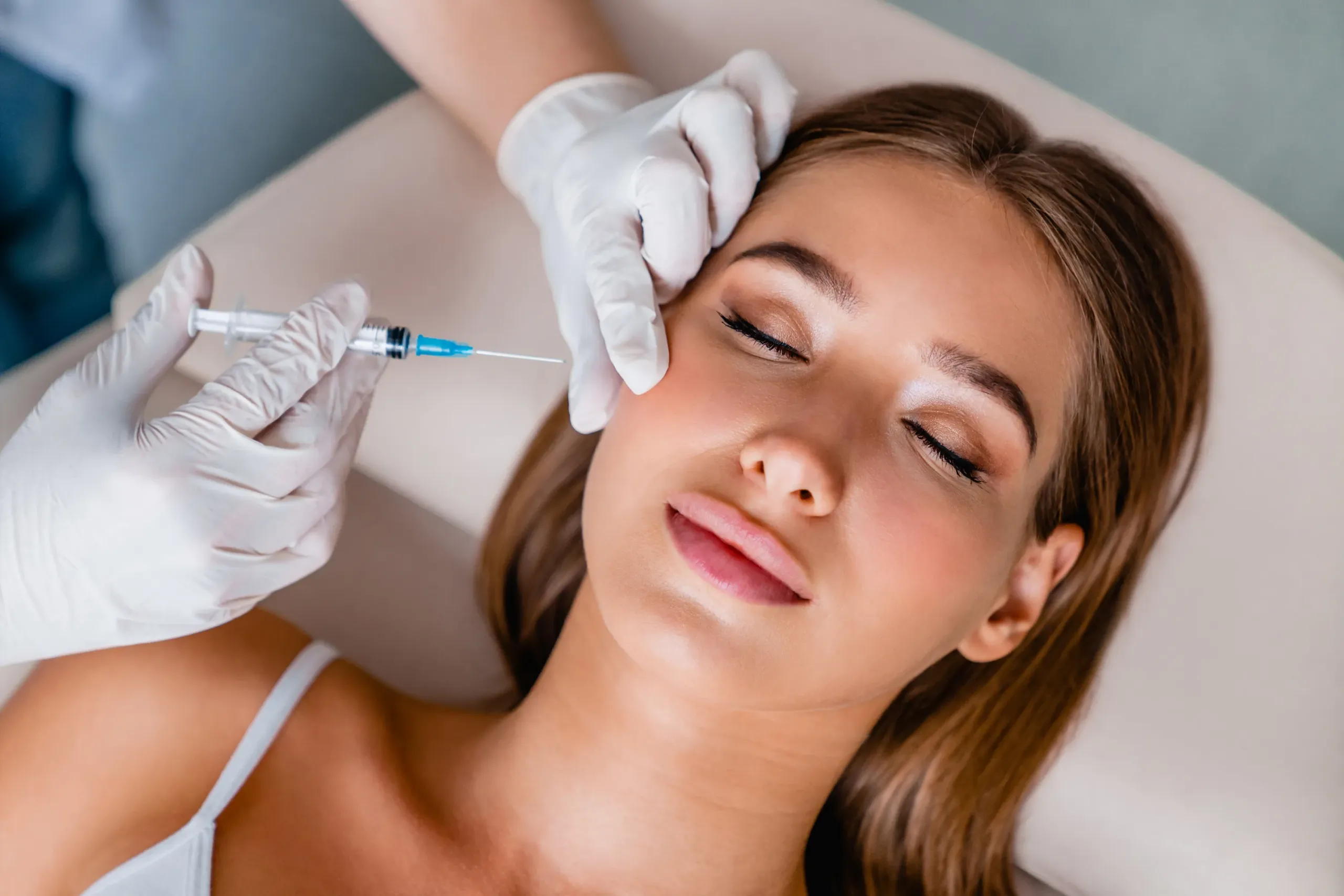 A gloved physician administering a Botox / Xeomin wrinkle-relaxer injection near the eye area